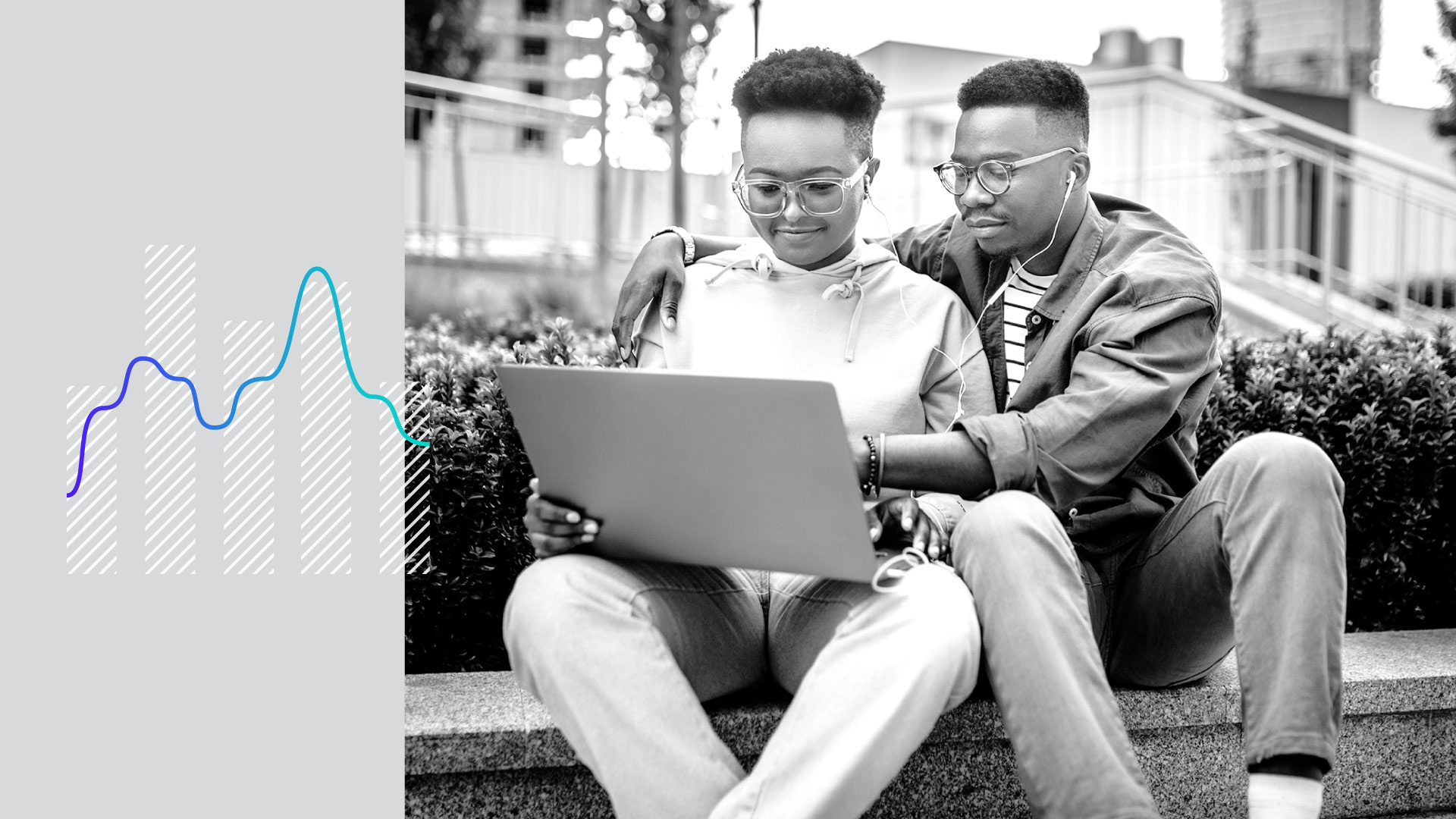 Two young people look at a laptop outside.